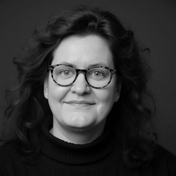 Cornelia Schmitz - Mentorin für Führungskräfte Porträt von Cornelia Schmitz. Frau mit lockigem Haar und Brille, lächelnd und mit klarem Blick.