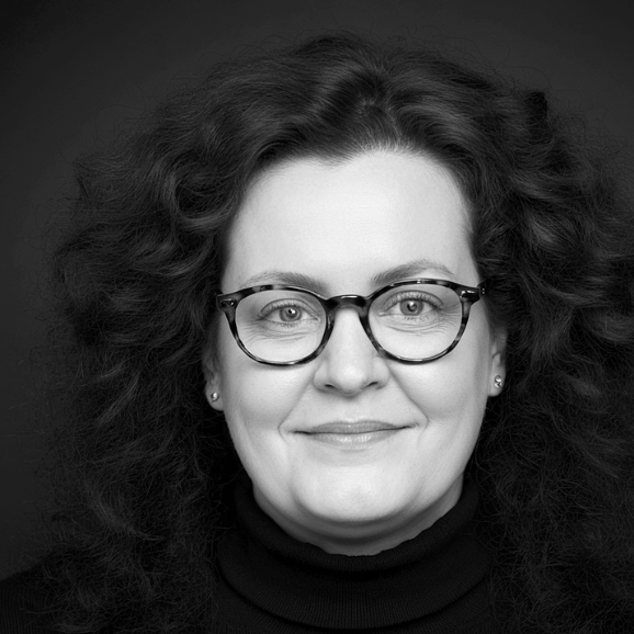 Cornelia Schmitz - Mentorin für Führungskräfte Porträt von Cornelia Schmitz. Eine Frau mit lockigem Haar und Brille, freundlich lächelnd und mit souveränem Blick.